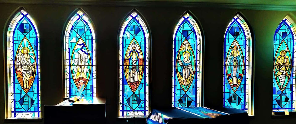 A stain glass wall depicting Mary the Mother of God on a dark background